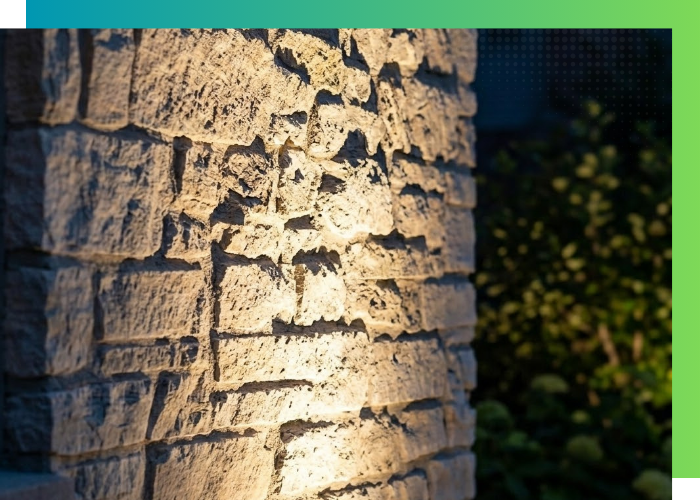 Close-up of a stone wall texture being illuminated from below by a hidden, professional-grade uplight fixture.